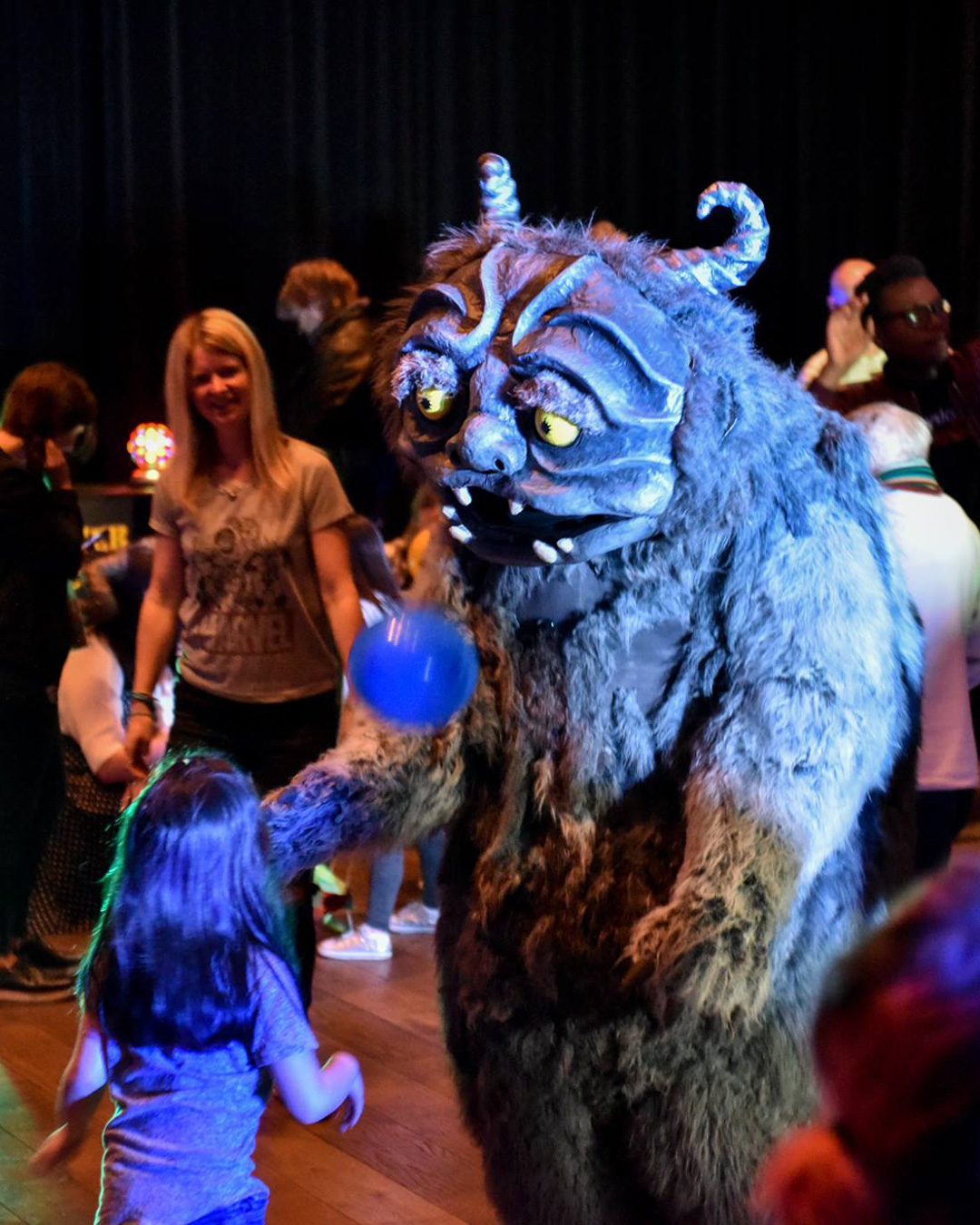 A child dancing with an adult in a monster costume