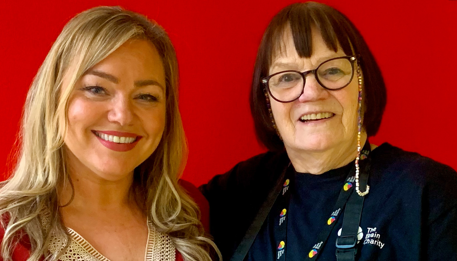 Two women. Kellyann and Rose standing against a plain red background