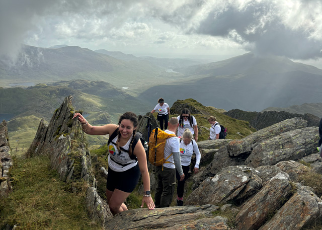 People in Brain Charity shirts scrambling over rocks on the way to the top of Mount Snowdon