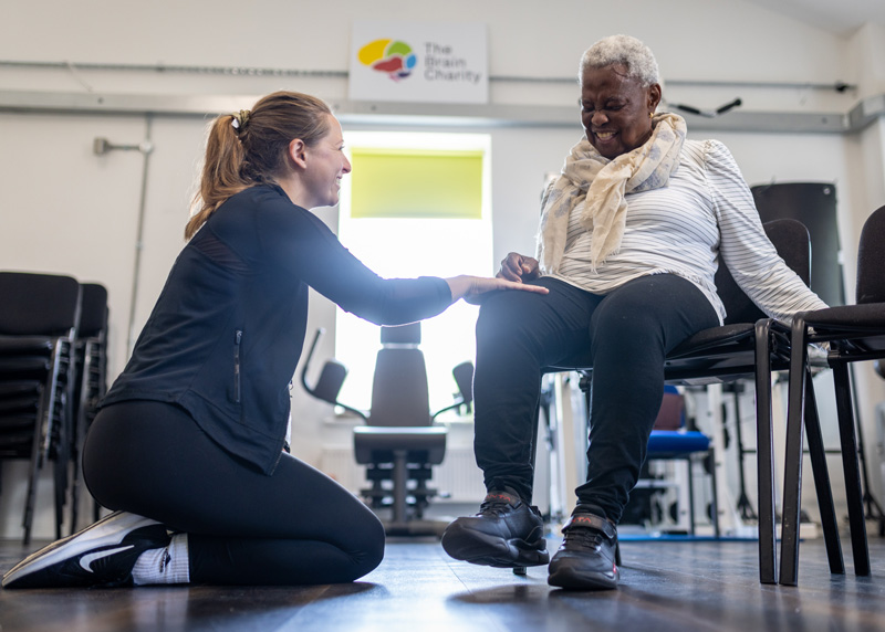 A physiotherapist helps a woman with her leg in The Brain Charity's Neuro Gym