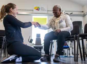 Woman seated and being instructed by a physiotherapist.