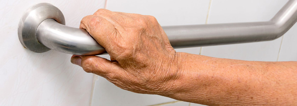 An old person's hand holding on to a rail for support