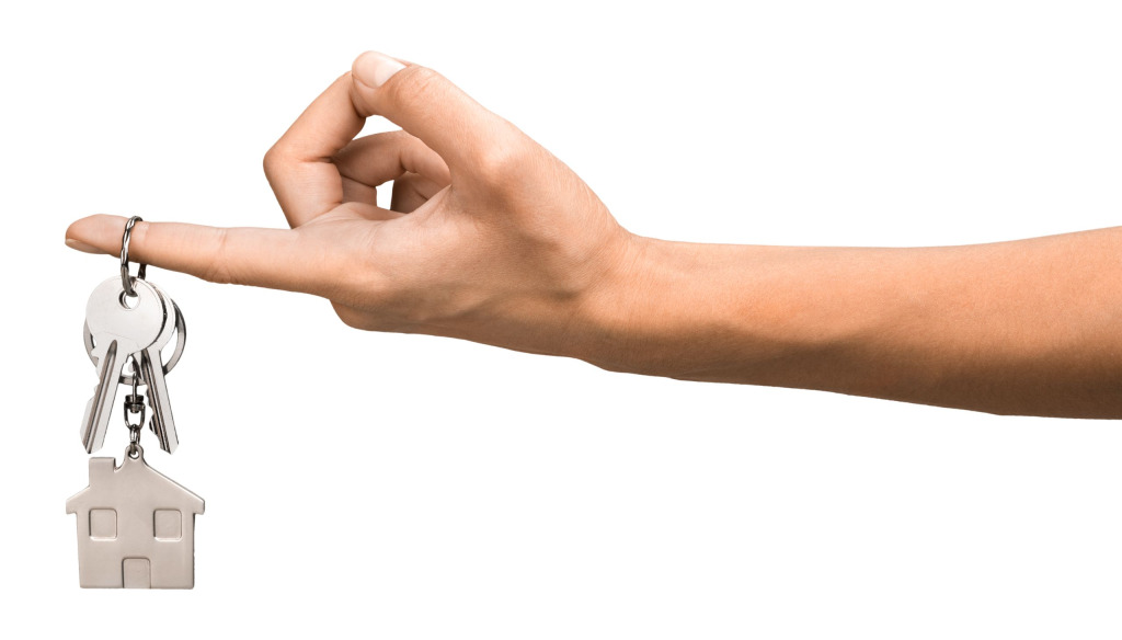 An outstretched woman's arm with a house key hanging from her finger