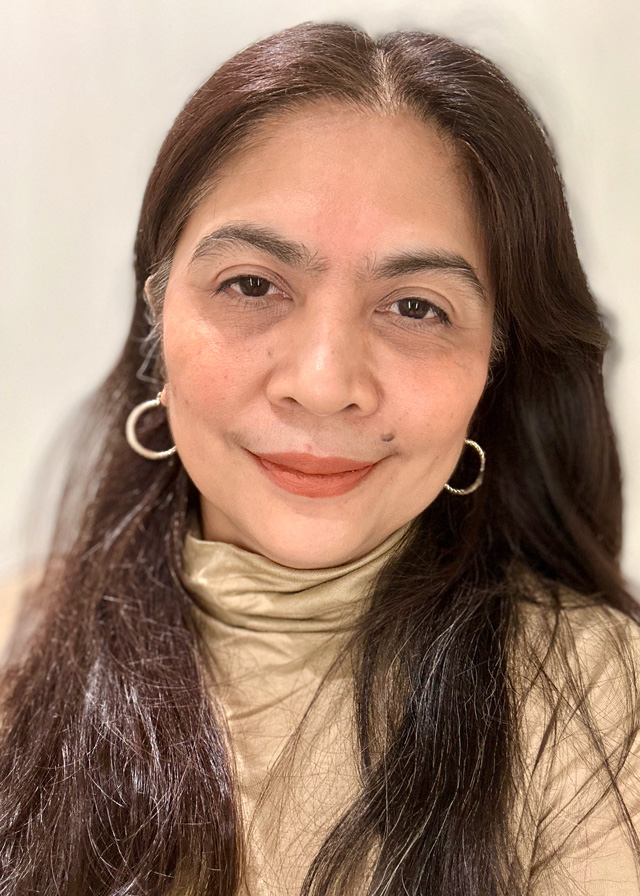 Woman with dark hair and hoop earrings smiling at camera