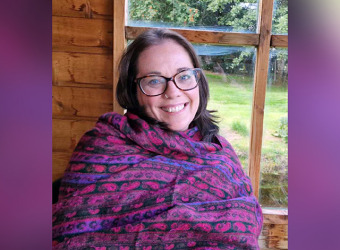 A middle aged woman in a purple shawl smiling at the camera