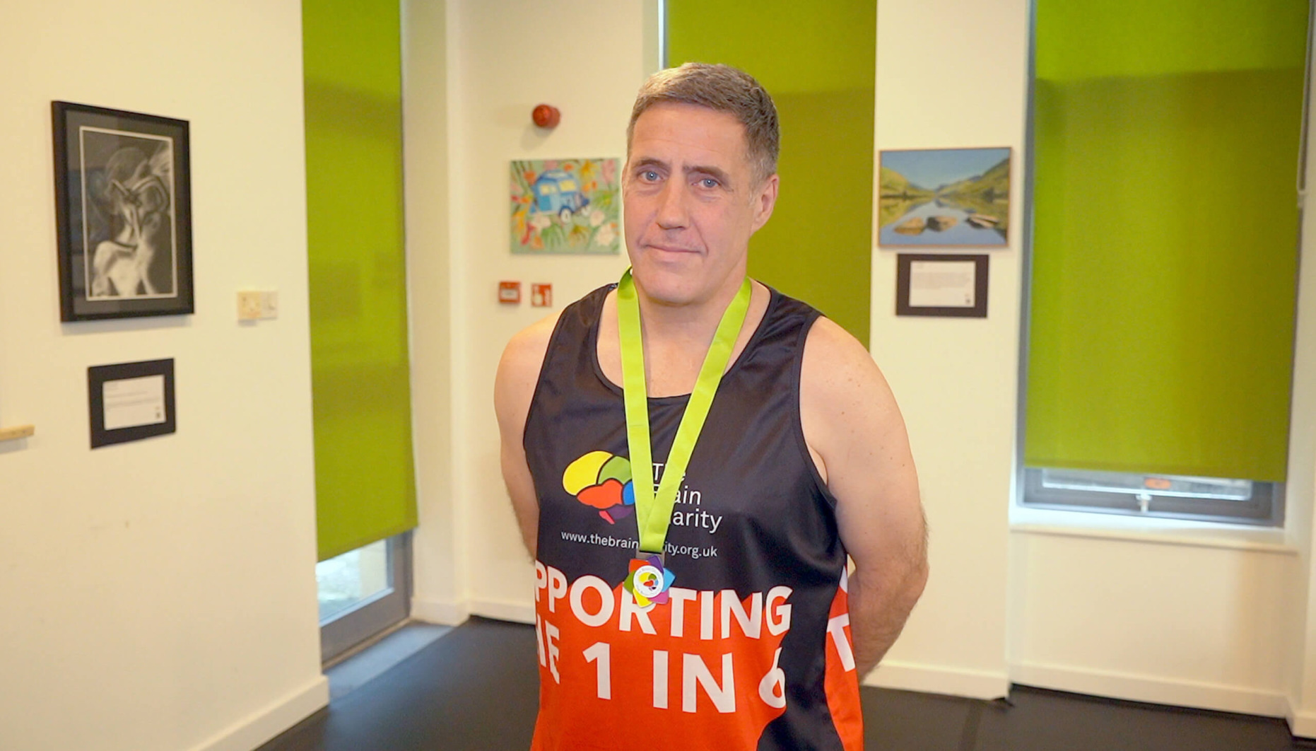 Neil, a man in his fifties, wearing his fundraisers medal following a presentation at The Brain Charity.