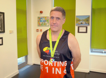 Neil, a man in his fifties, wearing his fundraisers medal following a presentation at The Brain Charity.