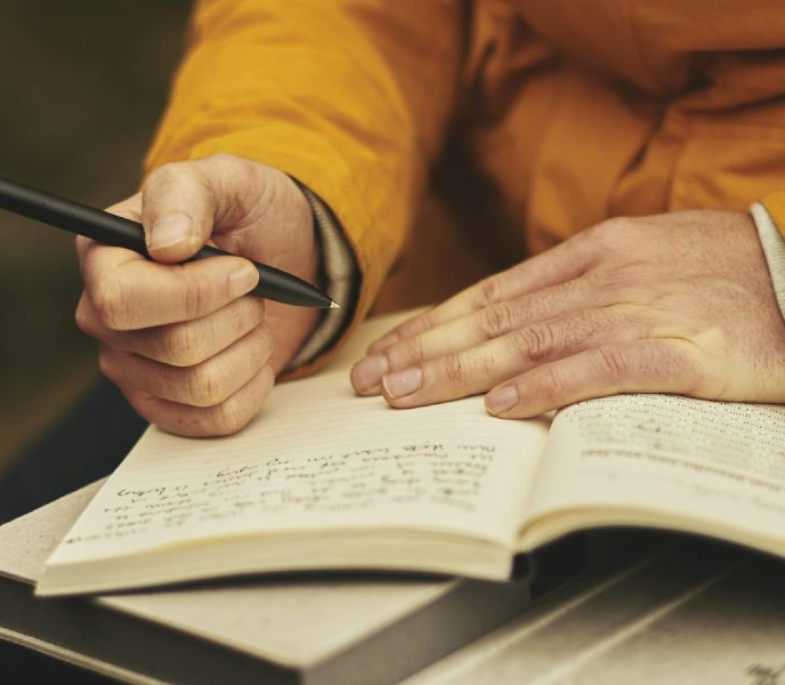 A close up of person's hands writing in a journal